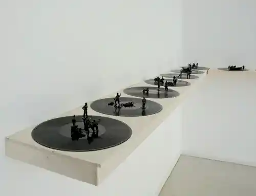 A row of vinyl records displayed on shelves with miniature battle figures placed on top.