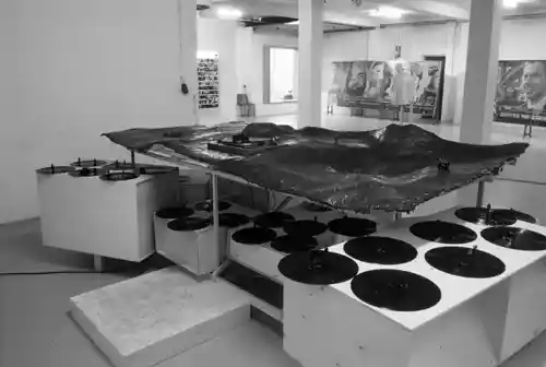 Art installation featuring turntables and a landscape-like structure in an exhibition space.