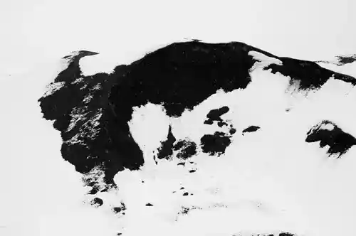 Close-up of a snowy slope in eastern Iceland, revealing the raw contrast of black coal and white snow.