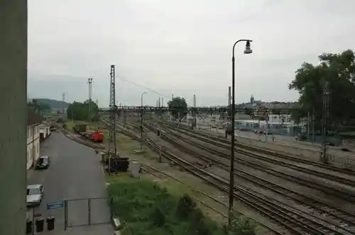 Overview of railway tracks and industrial landscape with overhead cables and nearby buildings.