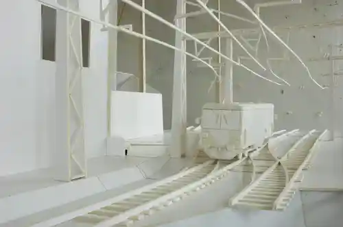 Close-up view of a white model train on miniature tracks with surrounding structures.