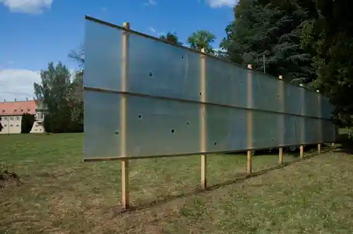 A translucent hunting blind installation on a grassy field, set against a backdrop of trees.