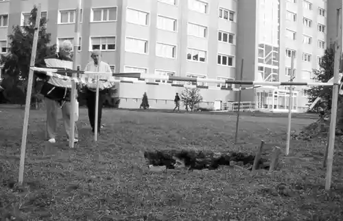 Closer view of the installation, showcasing the hole surrounded by urban buildings and spectators.